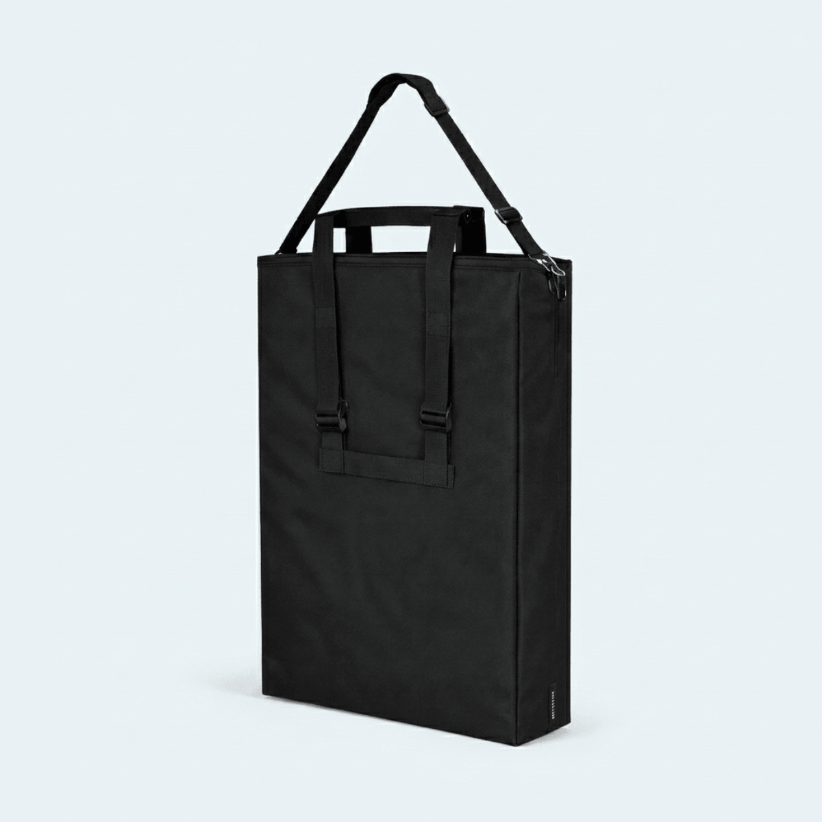 A black utility tote bag with dual top handles and an adjustable shoulder strap, shown on a light gray background.