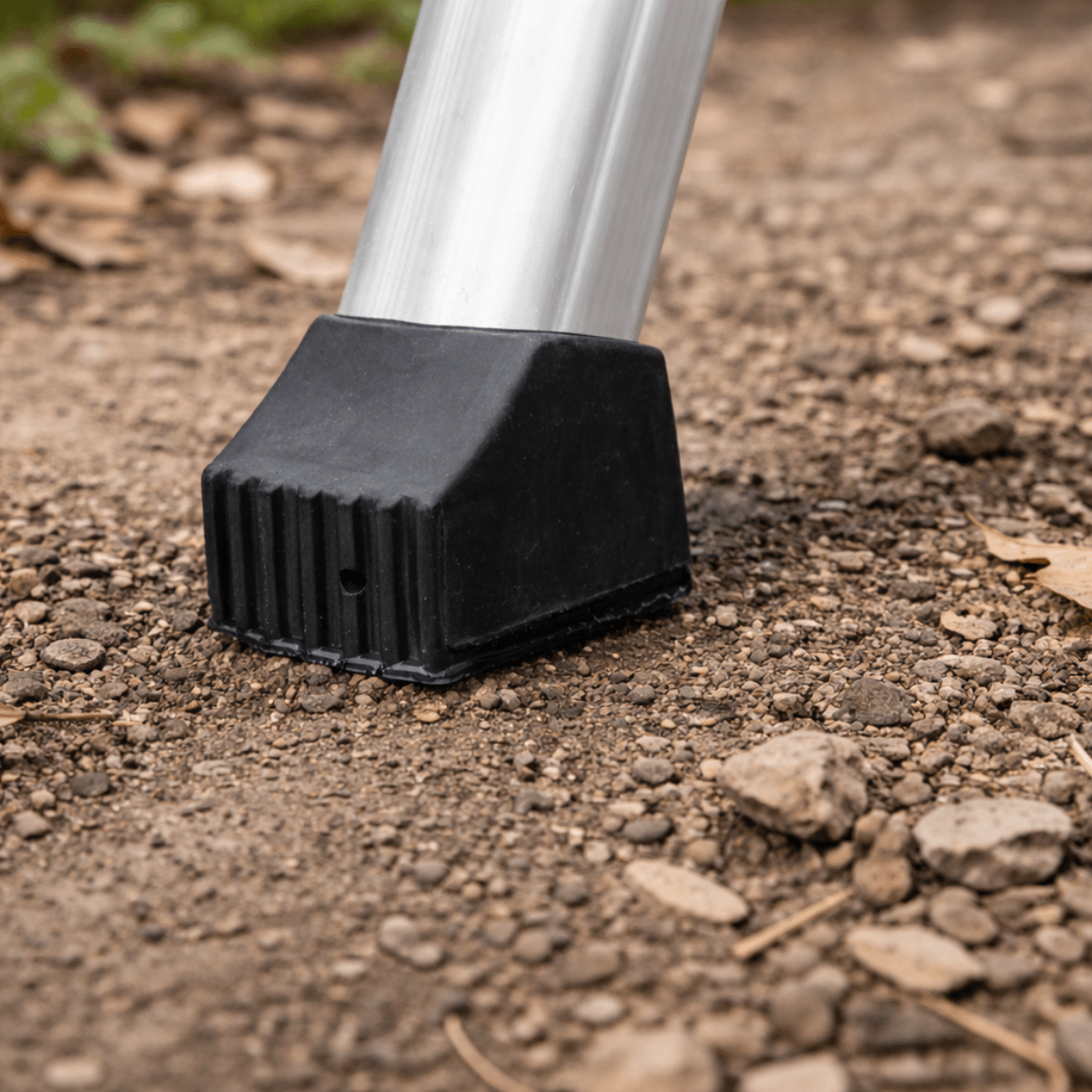 Black rubber foot on a metal leg pressing into dirt